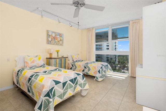 bedroom featuring track lighting, baseboards, tile patterned flooring, and a ceiling fan