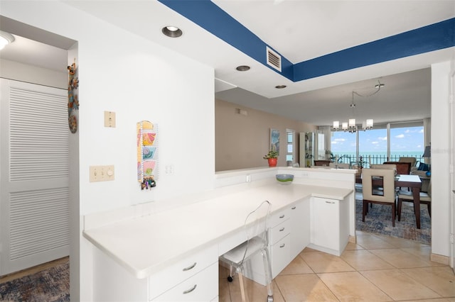 kitchen featuring an inviting chandelier, light countertops, visible vents, a peninsula, and white cabinetry