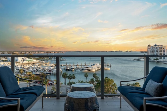 balcony at dusk featuring a water view
