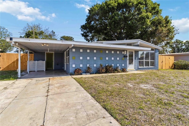 mid-century home with fence, an attached carport, driveway, and a front lawn