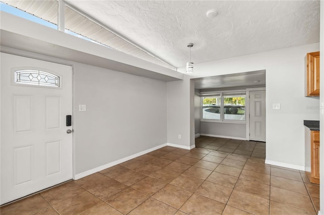 unfurnished dining area featuring light tile patterned floors, baseboards, and a textured ceiling