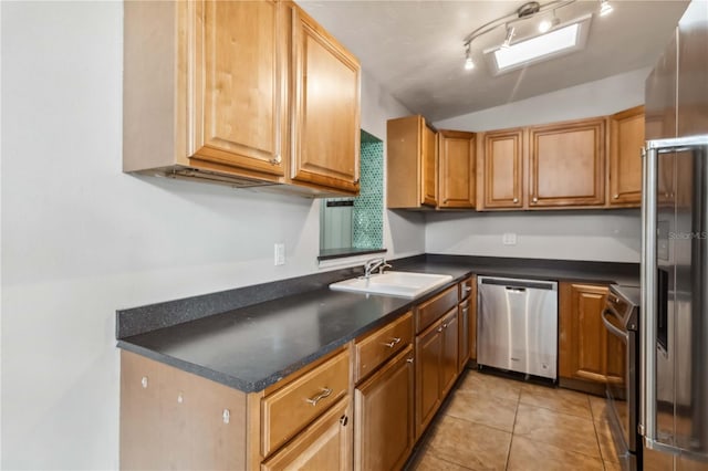kitchen featuring appliances with stainless steel finishes, dark countertops, vaulted ceiling, a sink, and light tile patterned floors
