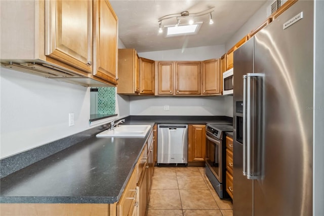 kitchen featuring dark countertops, appliances with stainless steel finishes, a sink, light tile patterned floors, and lofted ceiling