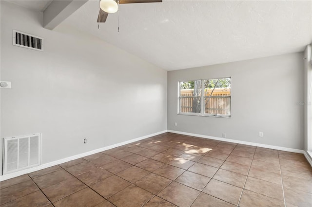 tiled empty room with visible vents, a ceiling fan, baseboards, and vaulted ceiling with beams