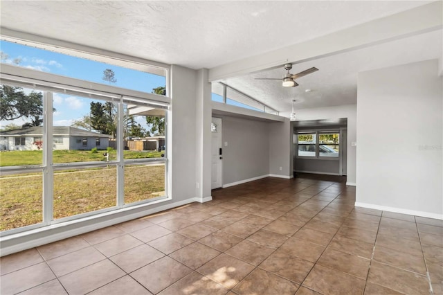interior space with tile patterned flooring, baseboards, ceiling fan, and vaulted ceiling