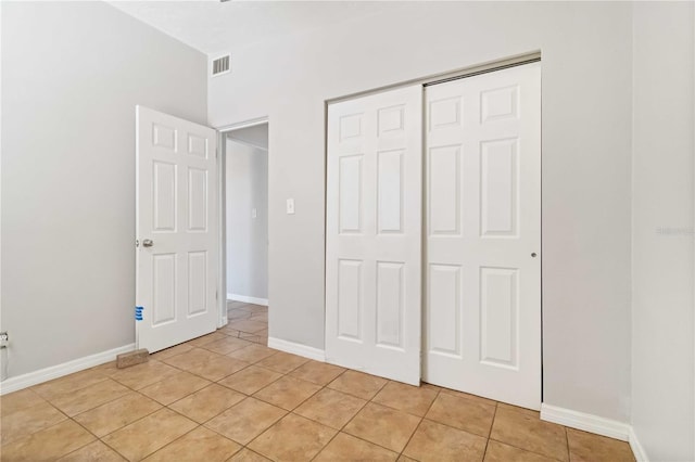 unfurnished bedroom with light tile patterned flooring, baseboards, visible vents, and a closet