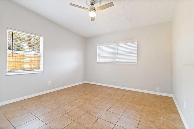 spare room featuring baseboards, ceiling fan, and light tile patterned floors
