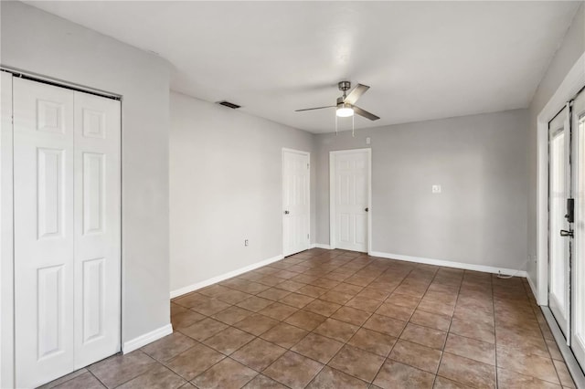 unfurnished bedroom with ceiling fan, visible vents, tile patterned flooring, baseboards, and a closet