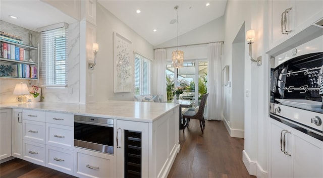 kitchen with vaulted ceiling, dark wood-style flooring, light stone counters, a notable chandelier, and wine cooler