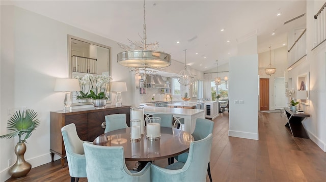 dining space featuring wood finished floors, lofted ceiling, baseboards, and a notable chandelier