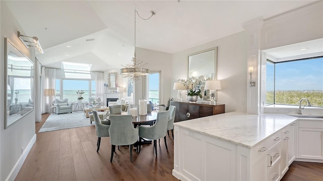 dining area with vaulted ceiling, a notable chandelier, wood finished floors, and a fireplace