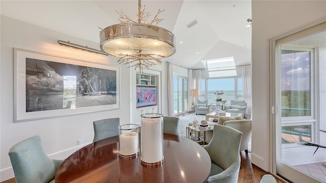 dining area featuring visible vents, wood finished floors, an inviting chandelier, and high vaulted ceiling