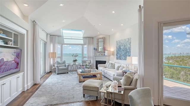 living room featuring lofted ceiling, a glass covered fireplace, a water view, and dark wood finished floors
