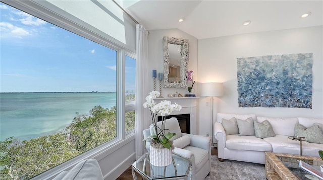 interior space with recessed lighting, vaulted ceiling, a fireplace, and a water view