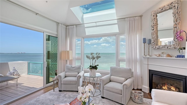 living area featuring a glass covered fireplace, wood finished floors, and a water view