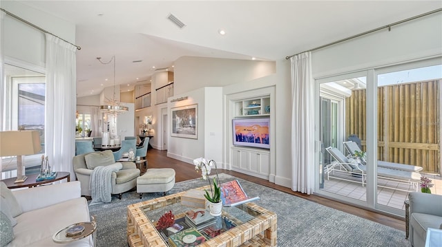 living area featuring recessed lighting, lofted ceiling, wood finished floors, visible vents, and a chandelier