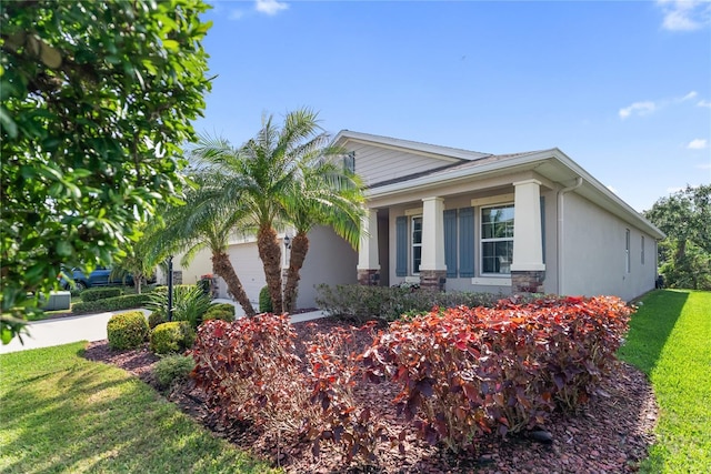 6124 35th Ct E, Bradenton, FL 34203 - view of home's exterior featuring a porch, stucco siding, a yard, a garage, and stone siding