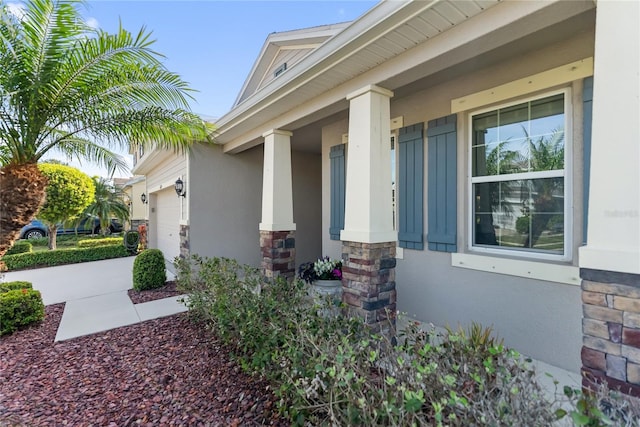 6124 35th Ct E, Bradenton, FL 34203 - view of property exterior featuring a porch, stucco siding, stone siding, concrete driveway, and an attached garage