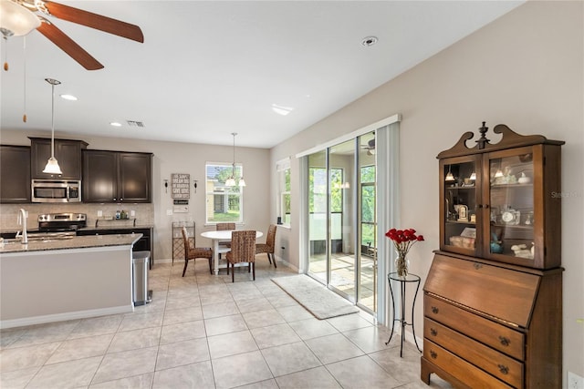 6124 35th Ct E, Bradenton, FL 34203 - kitchen featuring light stone counters, light tile patterned floors, decorative backsplash, stainless steel appliances, and a ceiling fan