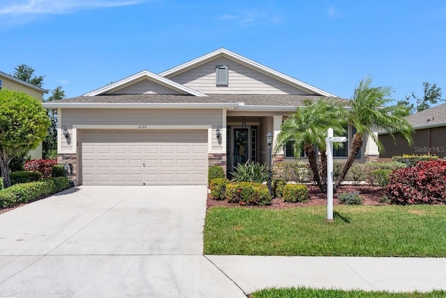 6124 35th Ct E, Bradenton, FL 34203 - view of front of house with stone siding, concrete driveway, a front lawn, and a garage