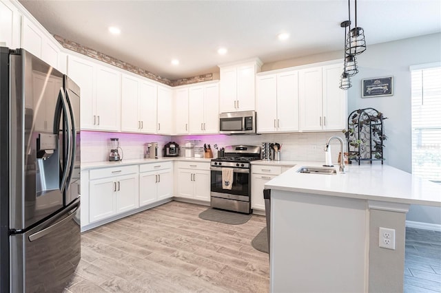 kitchen featuring tasteful backsplash, a sink, appliances with stainless steel finishes, a peninsula, and light wood-style flooring