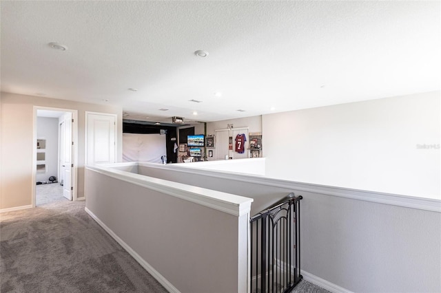 hall featuring carpet floors, baseboards, and an upstairs landing