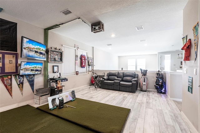 living area featuring visible vents, baseboards, a textured ceiling, and wood finished floors