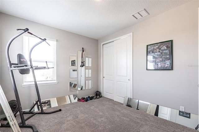 workout area featuring visible vents, a textured ceiling, and carpet floors