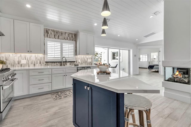 kitchen with light countertops, a breakfast bar area, decorative backsplash, stainless steel appliances, and a sink