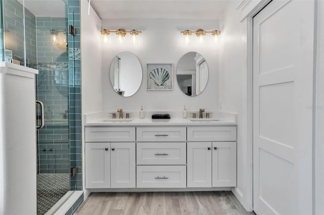 full bath with wood finished floors, a sink, a shower stall, and double vanity