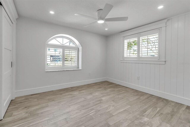 empty room featuring light wood-type flooring, a healthy amount of sunlight, baseboards, and ceiling fan