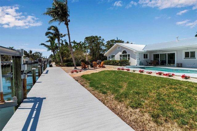 exterior space with a lawn, boat lift, a patio, and a pool with connected hot tub