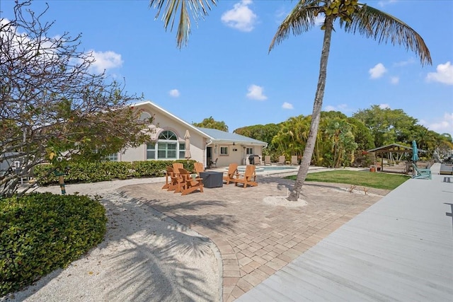 exterior space with an outdoor pool, a patio, and stucco siding