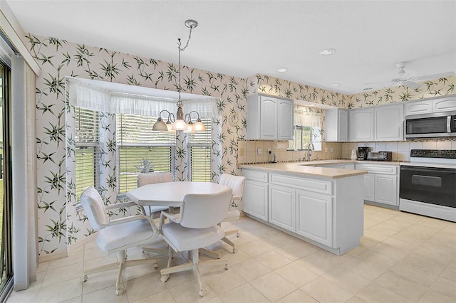4360 Presidential Avenue Cir E, Bradenton, FL 34203 - kitchen with electric range, wallpapered walls, stainless steel microwave, and a notable chandelier
