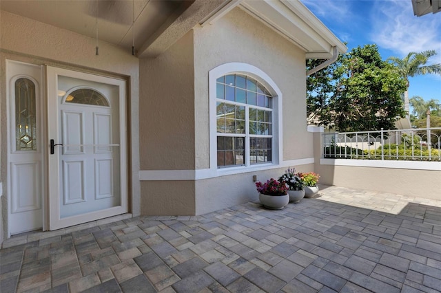 4044 Penshurst Park, Sarasota, FL 34235 - doorway to property featuring fence, a patio, and stucco siding