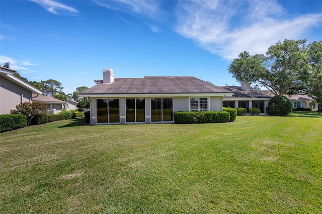 4044 Penshurst Park, Sarasota, FL 34235 - back of house with stucco siding, a chimney, and a lawn