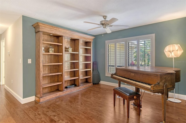 living area with wood finished floors, baseboards, and ceiling fan