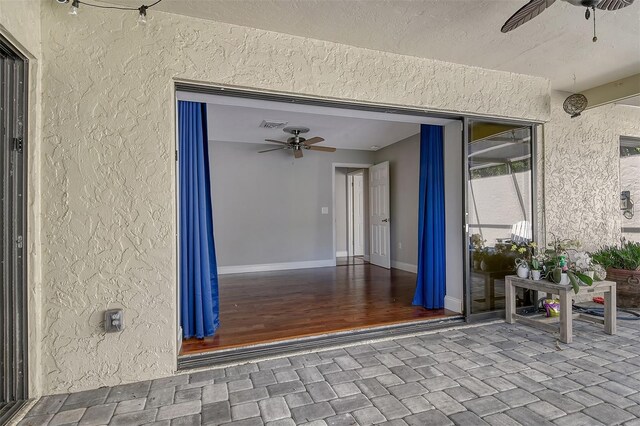 entrance to property with a ceiling fan and stucco siding