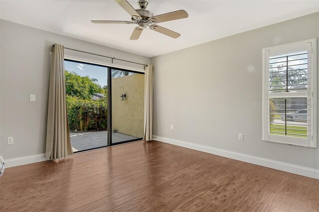 empty room featuring ceiling fan, a wealth of natural light, wood finished floors, and baseboards