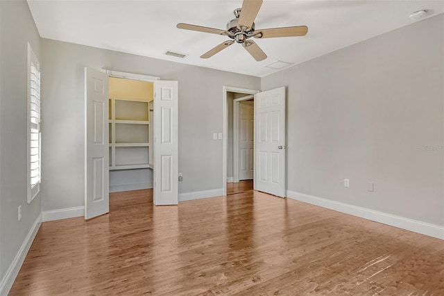 unfurnished bedroom featuring light wood-type flooring, a ceiling fan, baseboards, and visible vents