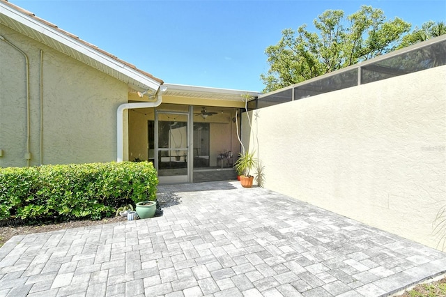 doorway to property featuring a patio area, ceiling fan, and stucco siding