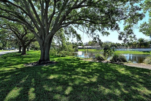 surrounding community with a water view and a yard
