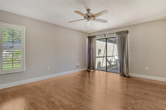 empty room with wood finished floors, a textured ceiling, baseboards, and ceiling fan