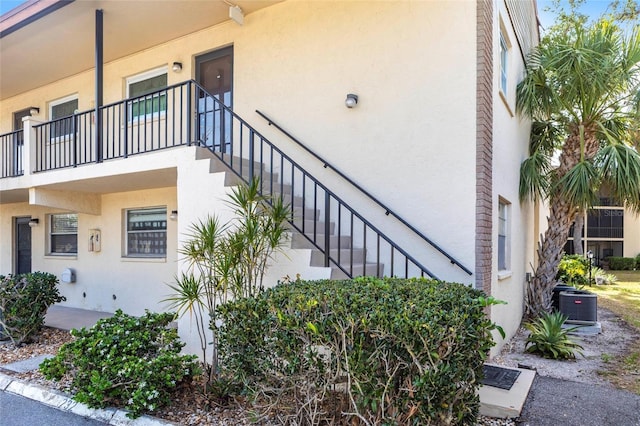 2300 Stickney Point Rd Unit 125, Sarasota, FL 34231 - view of property exterior featuring stairs, stucco siding, and cooling unit