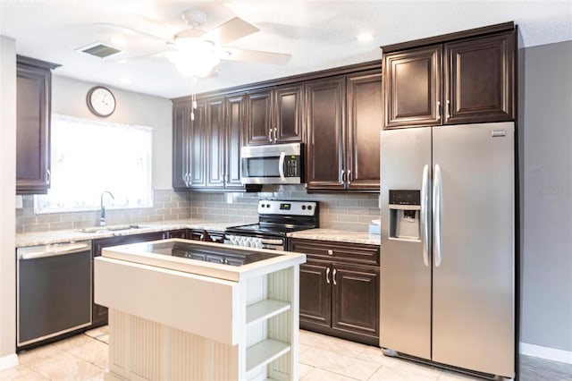 2300 Stickney Point Rd Unit 125, Sarasota, FL 34231 - kitchen with appliances with stainless steel finishes, a sink, dark brown cabinets, backsplash, and a center island