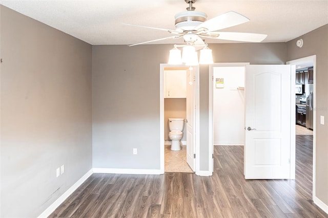 2300 Stickney Point Rd Unit 125, Sarasota, FL 34231 - unfurnished bedroom featuring a spacious closet, wood finished floors, and baseboards