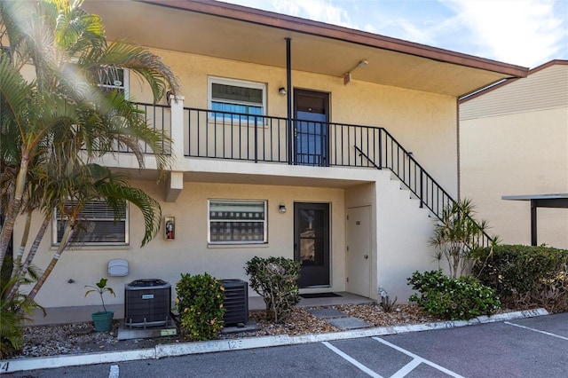 2300 Stickney Point Rd Unit 125, Sarasota, FL 34231 - entrance to property with stucco siding, central AC, uncovered parking, and a balcony