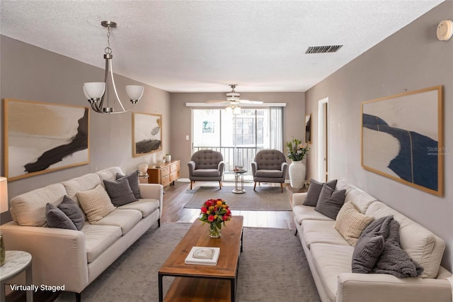 2300 Stickney Point Rd Unit 125, Sarasota, FL 34231 - living room with wood finished floors, a textured ceiling, a chandelier, and baseboards