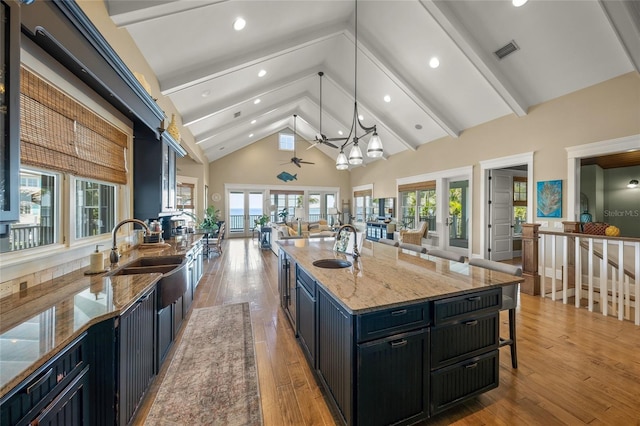 526 56th St, Holmes Beach, FL 34217 - kitchen featuring open floor plan, visible vents, dark cabinetry, high vaulted ceiling, and a sink