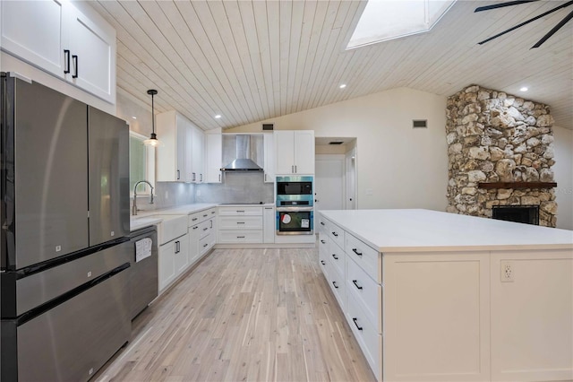 4916 Hidden Oaks Trl, Sarasota, FL 34232 - kitchen featuring appliances with stainless steel finishes, lofted ceiling, a skylight, light wood-style flooring, and wall chimney exhaust hood